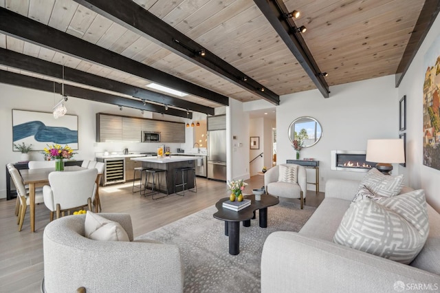56 Aztec St, San Francisco, CA 94110 - living area featuring track lighting, light wood-style flooring, wood ceiling with exposed beams, wine cooler, and a glass covered fireplace