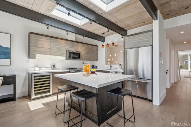 56 Aztec St, San Francisco, CA 94110 - kitchen featuring built in appliances, wine cooler, rail lighting, a breakfast bar area, and light wood-style floors