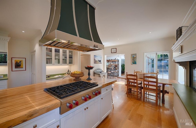 3850 Montecito Ave, Santa Rosa, CA 95404 - kitchen with stainless steel gas stovetop, wall chimney exhaust hood, crown molding, white cabinetry, and light wood-type flooring