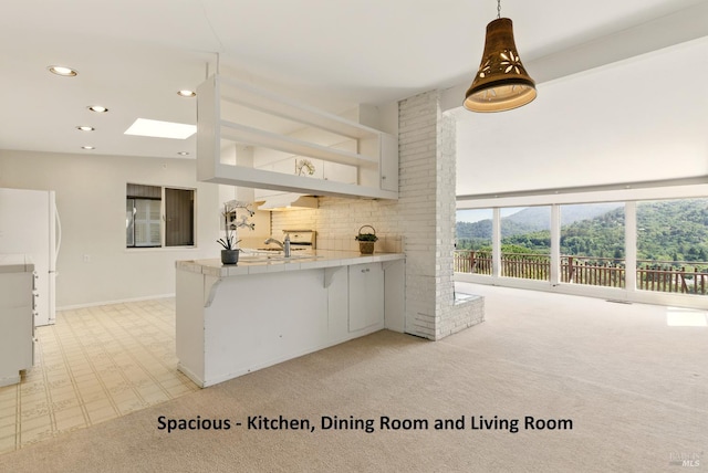 175 Ridge Rd, San Anselmo, CA 94960 - kitchen featuring light colored carpet, freestanding refrigerator, a peninsula, recessed lighting, and tile counters