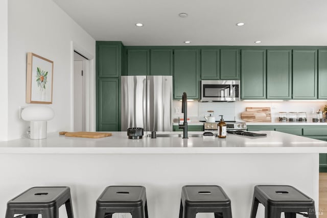 34 Laurel Dr, Corte Madera, CA 94925 - kitchen with green cabinetry, appliances with stainless steel finishes, light countertops, a breakfast bar, and recessed lighting