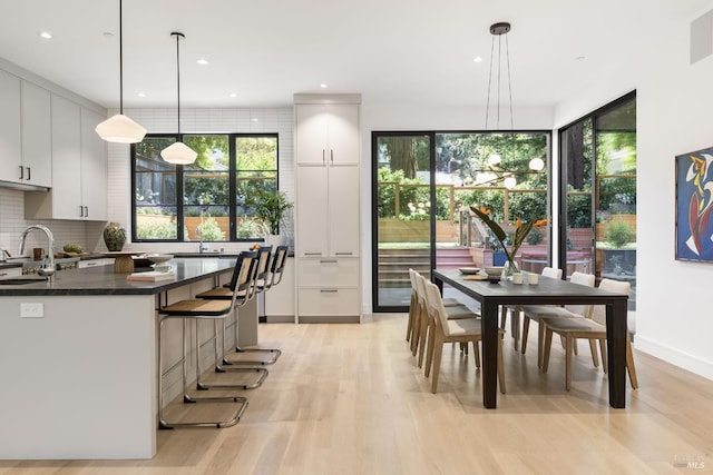 225 W Baltimore Ave, Larkspur, CA 94939 - kitchen with light wood-type flooring, backsplash, white cabinetry, pendant lighting, and a sink