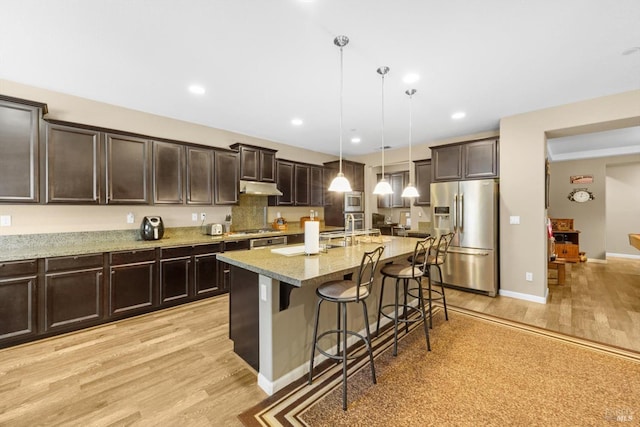 2234 Pullen Ln, Fairfield, CA 94533 - kitchen featuring appliances with stainless steel finishes, under cabinet range hood, light wood-style flooring, a breakfast bar area, and recessed lighting