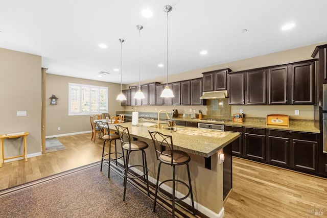 2234 Pullen Ln, Fairfield, CA 94533 - kitchen with a sink, a kitchen breakfast bar, under cabinet range hood, light wood finished floors, and light stone countertops