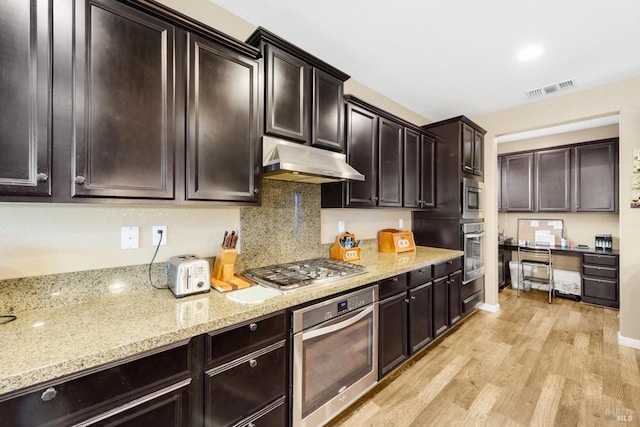 2234 Pullen Ln, Fairfield, CA 94533 - kitchen featuring stainless steel appliances, under cabinet range hood, light wood-type flooring, light stone counters, and dark brown cabinetry
