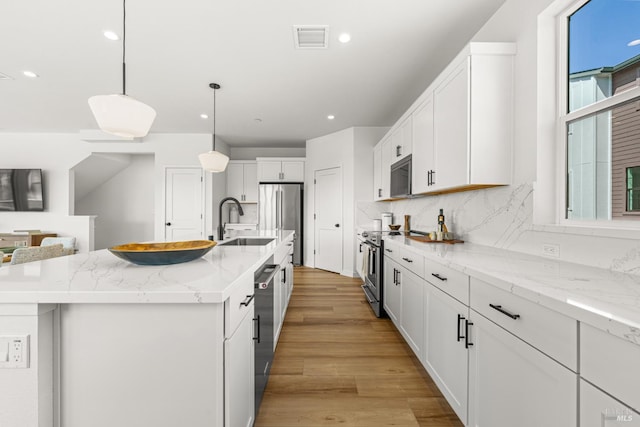 1480 Waterside Ln, Rohnert Park, CA 94928 - kitchen with appliances with stainless steel finishes, a sink, white cabinetry, a center island with sink, and light wood-style flooring