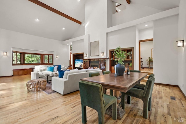 192 Carson Rd, Woodacre, CA 94973 - dining area with high vaulted ceiling, beam ceiling, light wood-style floors, a glass covered fireplace, and baseboards