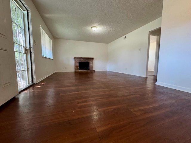 5972 Walerga Rd Unit 1, Sacramento, CA 95842 - unfurnished living room featuring dark wood finished floors, a textured ceiling, a brick fireplace, and baseboards