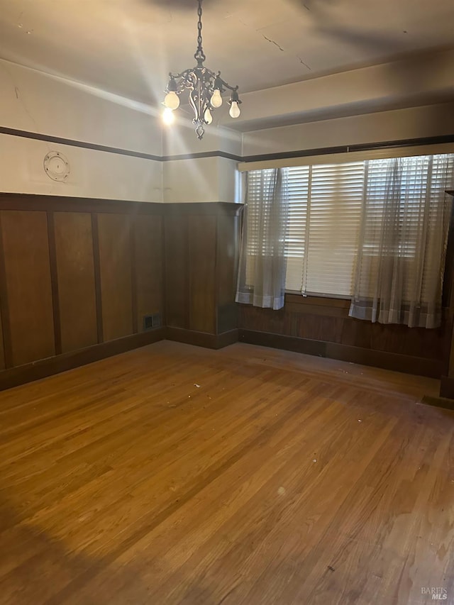 718 Monterey St, Vallejo, CA 94590 - unfurnished room with wood finished floors, a chandelier, and a decorative wall