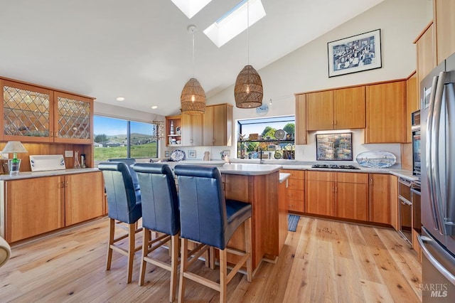 21199 Hummingbird Ct, Bodega Bay, CA 94923 - kitchen featuring a skylight, high vaulted ceiling, light wood-style flooring, light countertops, and a breakfast bar