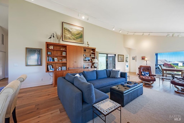 21199 Hummingbird Ct, Bodega Bay, CA 94923 - living area featuring rail lighting, wood finished floors, a towering ceiling, and baseboards