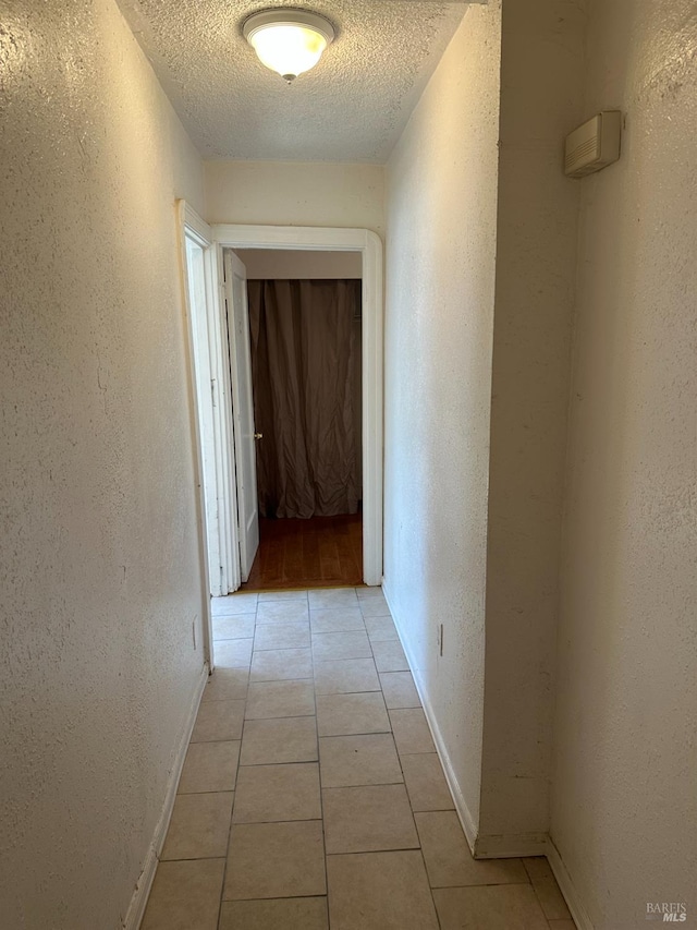 942 Benicia Rd, Vallejo, CA 94591 - hall featuring a textured wall, a textured ceiling, light tile patterned floors, and baseboards