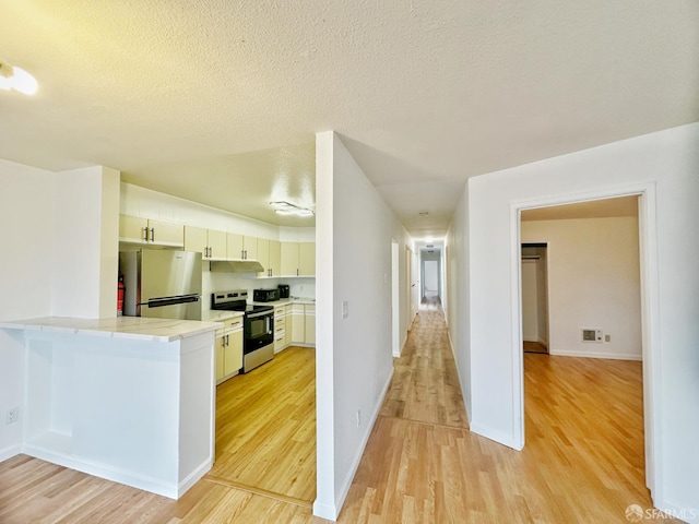 1927 Taraval St, San Francisco, CA 94116 - kitchen with stainless steel appliances, light wood finished floors, light countertops, a peninsula, and a textured ceiling