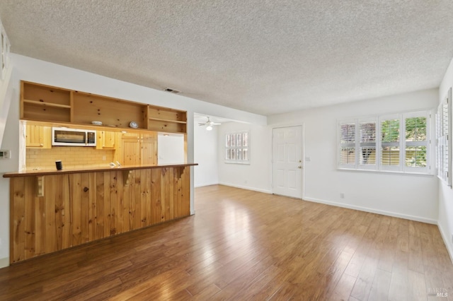 38 Plumas Cir, Novato, CA 94947 - kitchen featuring stainless steel microwave, a textured ceiling, open shelves, wood finished floors, and a peninsula