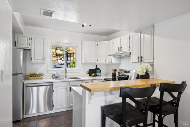 1259 Royal Oak Ter Unit A, Novato, CA 94947 - kitchen featuring stainless steel appliances, a sink, under cabinet range hood, a breakfast bar area, and white cabinets