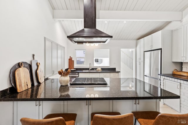 2647 Heatherstone Dr, San Rafael, CA 94903 - kitchen with a sink, island exhaust hood, stainless steel fridge, a kitchen bar, and wooden ceiling with exposed beams