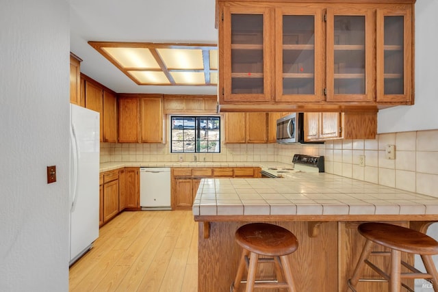 19828 Greenview Dr, Twain Harte, CA 95383 - kitchen with white appliances, a peninsula, brown cabinetry, light wood finished floors, and tasteful backsplash