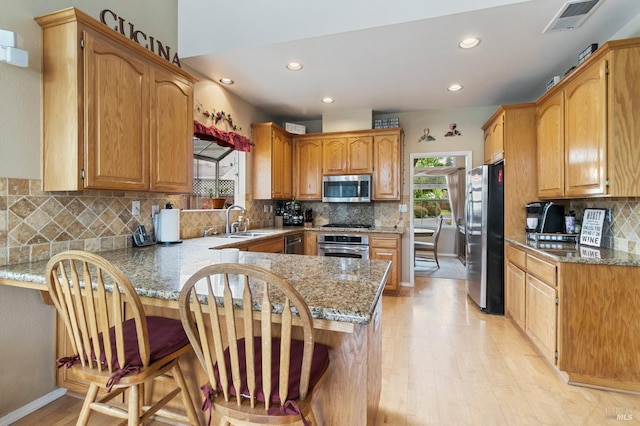 809 Muscat Ct, Petaluma, CA 94954 - kitchen with appliances with stainless steel finishes, a peninsula, a sink, light wood finished floors, and decorative backsplash