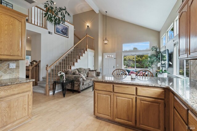 809 Muscat Ct, Petaluma, CA 94954 - kitchen with high vaulted ceiling, a peninsula, light stone counters, light wood-style floors, and decorative backsplash