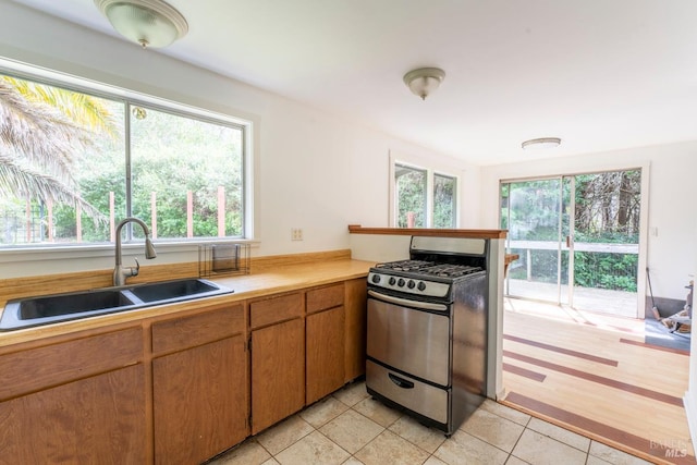 43390 Comptche Ukiah Rd, Mendocino, CA 95460 - kitchen featuring stainless steel gas range oven, a sink, light countertops, light tile patterned floors, and brown cabinets