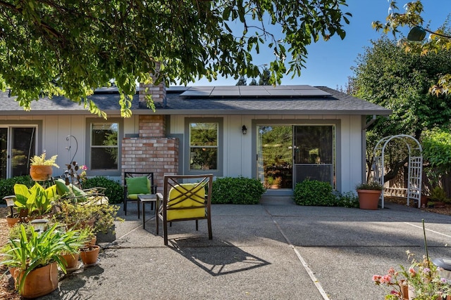 2010 Caulfield Ln, Petaluma, CA 94954 - rear view of house featuring a patio, roof mounted solar panels, board and batten siding, and roof with shingles
