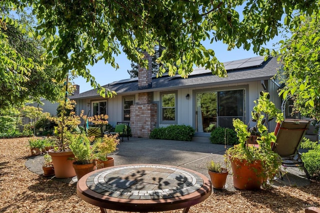 2010 Caulfield Ln, Petaluma, CA 94954 - view of front of property featuring solar panels, a fire pit, board and batten siding, a patio, and a chimney