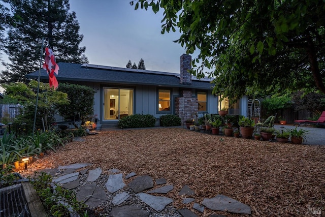 2010 Caulfield Ln, Petaluma, CA 94954 - view of front of home featuring roof mounted solar panels, a chimney, and board and batten siding