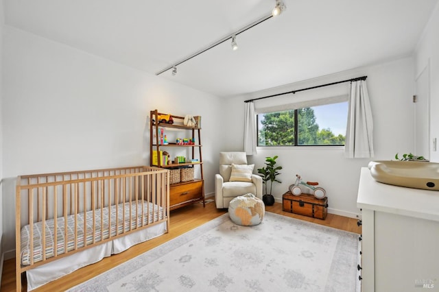 110 Morning Sun Ave, Mill Valley, CA 94941 - bedroom featuring rail lighting, wood finished floors, a crib, and a sink
