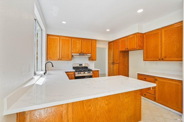 2752 Hillview Dr, Fairfield, CA 94534 - kitchen with stainless steel gas range, a sink, under cabinet range hood, light stone countertops, and brown cabinetry