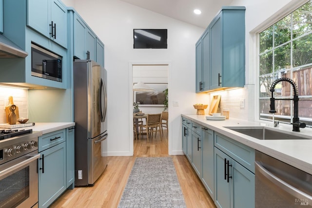 90 George Ln, Sausalito, CA 94965 - kitchen with appliances with stainless steel finishes, a sink, blue cabinets, light wood-type flooring, and light countertops