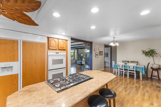 20320 Hollands Ln, Willits, CA 95490 - kitchen with double oven, gas cooktop, light countertops, a chandelier, and a kitchen bar