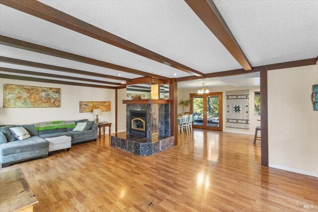 20320 Hollands Ln, Willits, CA 95490 - living room featuring beamed ceiling, light wood-style floors, baseboards, a tile fireplace, and a textured ceiling