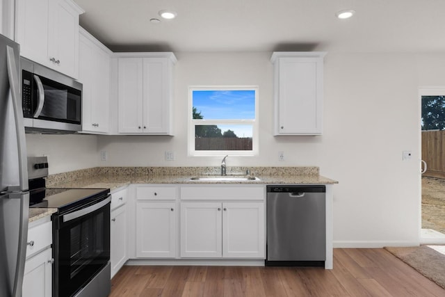 6601 Jackpot Pl, Riverbank, CA 95367 - kitchen featuring appliances with stainless steel finishes, a sink, light wood-style flooring, white cabinets, and light stone counters