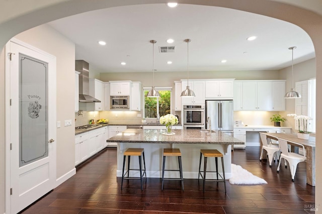 907 Serendipity Way, Napa, CA 94558 - kitchen featuring wall chimney exhaust hood, stainless steel appliances, arched walkways, a center island, and a breakfast bar