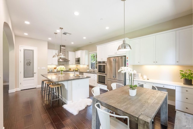 907 Serendipity Way, Napa, CA 94558 - kitchen with stainless steel appliances, wall chimney exhaust hood, a center island with sink, dark wood-style floors, and white cabinets