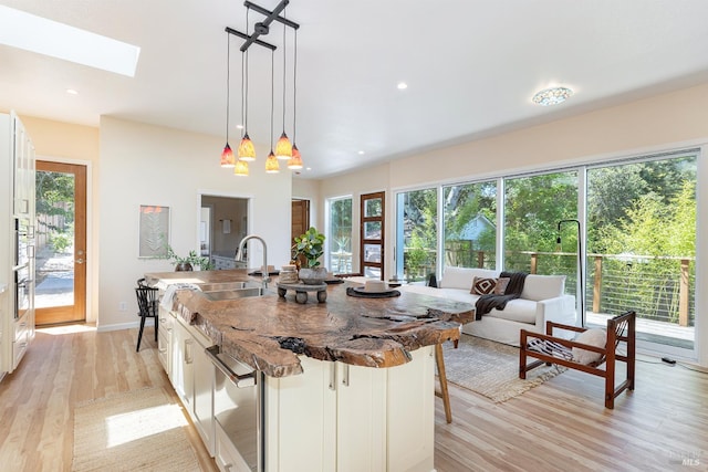 660 S Main St, Sebastopol, CA 95472 - kitchen with light wood-style flooring, a kitchen island with sink, a skylight, white cabinetry, and recessed lighting