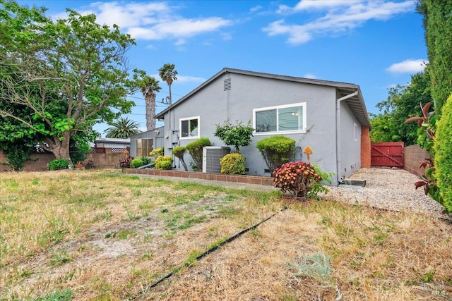 view of side of home with stucco siding and a gate
