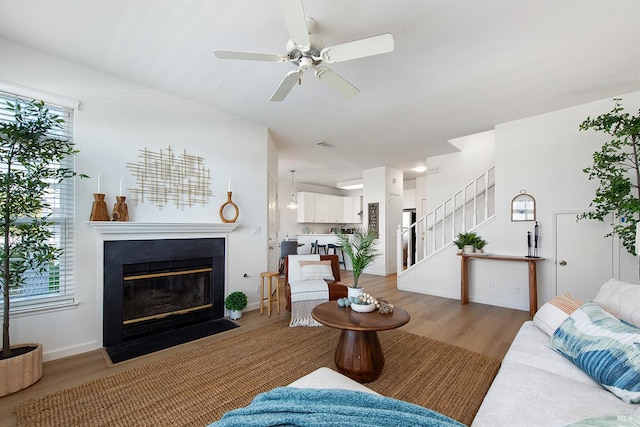 306 Commodore Dr, Richmond, CA 94804 - living area featuring stairway, light wood finished floors, a fireplace with flush hearth, a ceiling fan, and healthy amount of natural light