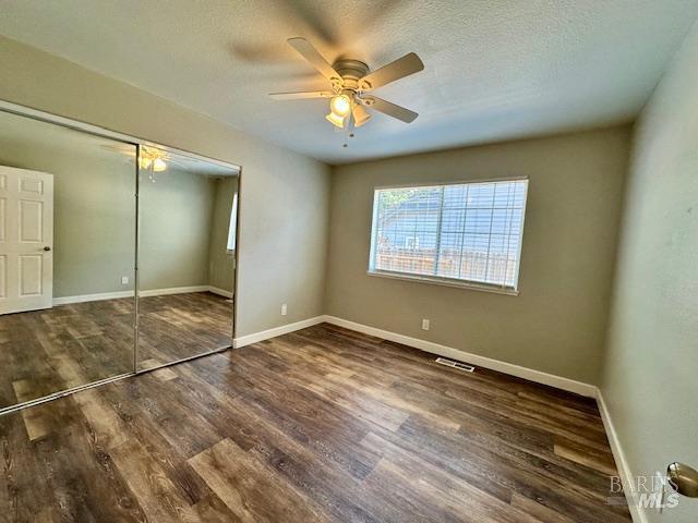 1540 Mccarthy Ct, Dixon, CA 95620 - unfurnished bedroom with wood finished floors, a closet, ceiling fan, and a textured ceiling
