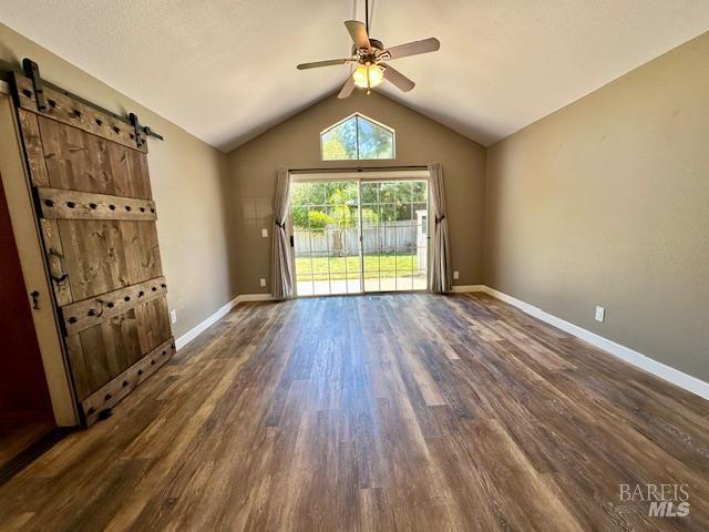 1540 Mccarthy Ct, Dixon, CA 95620 - unfurnished room with dark wood-type flooring, a ceiling fan, lofted ceiling, and a barn door
