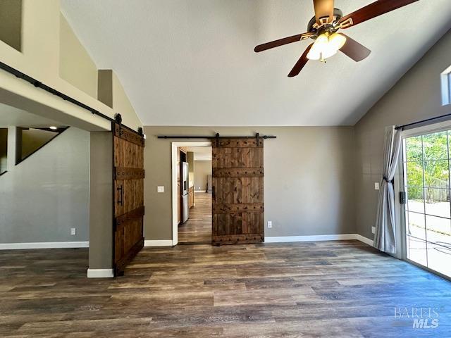 1540 Mccarthy Ct, Dixon, CA 95620 - empty room featuring a barn door, wood finished floors, high vaulted ceiling, and a ceiling fan