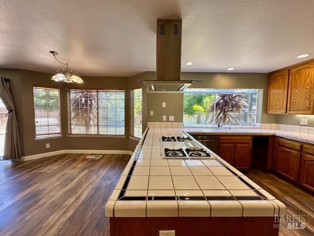 1540 Mccarthy Ct, Dixon, CA 95620 - kitchen featuring tile countertops, island exhaust hood, white gas stovetop, a textured ceiling, and dark wood-type flooring