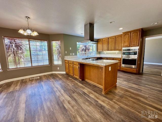 1540 Mccarthy Ct, Dixon, CA 95620 - kitchen with double oven, wall chimney range hood, a peninsula, brown cabinets, and recessed lighting