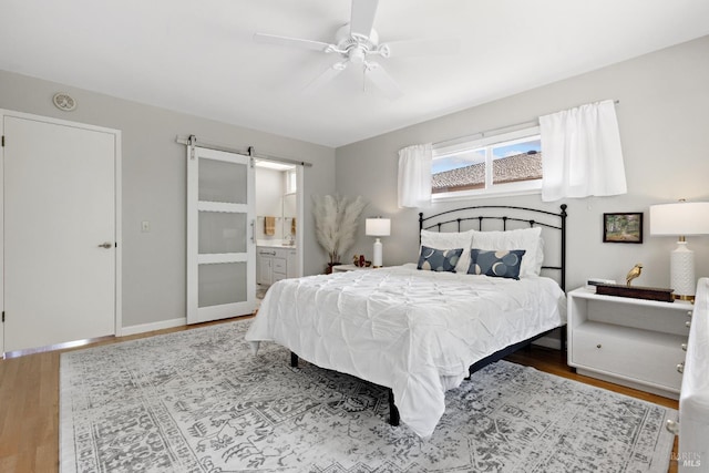 6518 Meadowgreen Pl, Santa Rosa, CA 95409 - bedroom featuring a barn door, wood finished floors, ensuite bathroom, baseboards, and ceiling fan