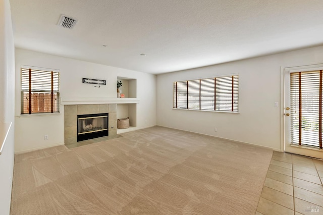 8046 Mason Dr, Rohnert Park, CA 94928 - unfurnished living room featuring a tiled fireplace, plenty of natural light, light carpet, and light tile patterned floors