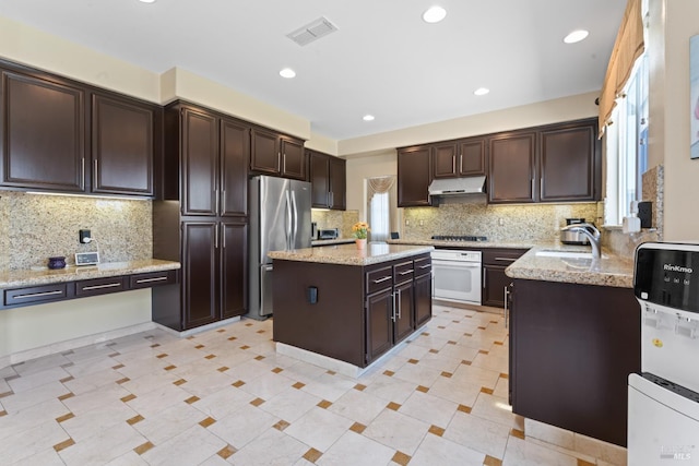 473 Mccall Dr, Benicia, CA 94510 - kitchen with white oven, freestanding refrigerator, a sink, under cabinet range hood, and backsplash