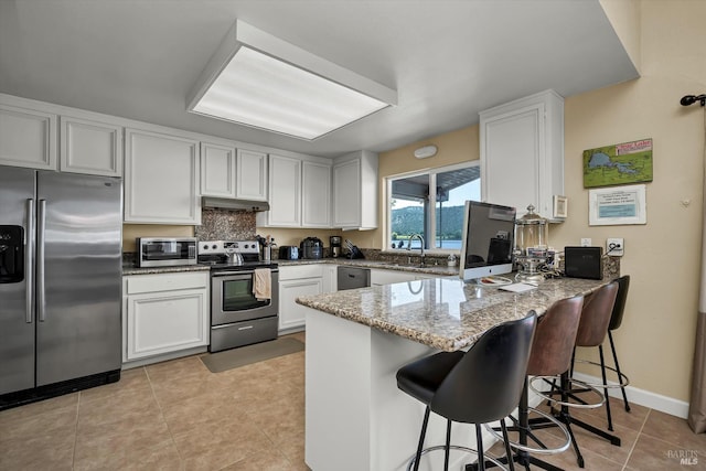 13201 Keys Blvd, Clearlake Oaks, CA 95423 - kitchen with stainless steel appliances, under cabinet range hood, a peninsula, light stone counters, and a sink