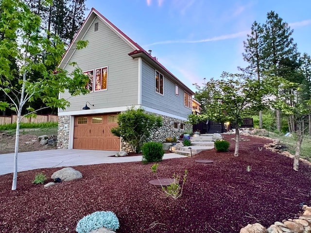 9 Spring Meadows Rd, Mccloud, CA 96507 - view of property exterior featuring stone siding, driveway, and a garage