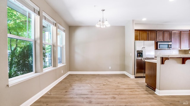 9149 Windsor Rd, Windsor, CA 95492 - kitchen with appliances with stainless steel finishes, a kitchen breakfast bar, light wood finished floors, a chandelier, and decorative light fixtures