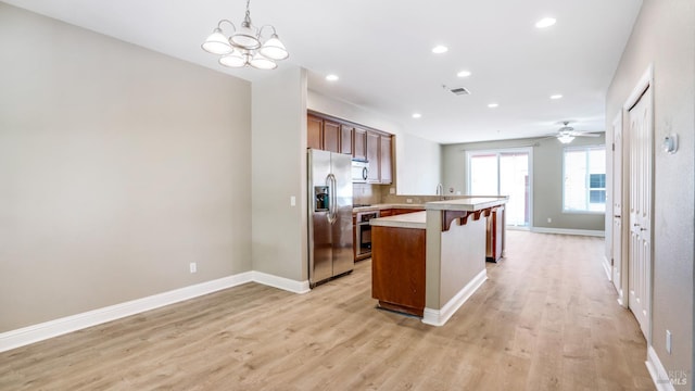 9149 Windsor Rd, Windsor, CA 95492 - kitchen with stainless steel appliances, a kitchen bar, light wood-style flooring, light countertops, and a peninsula